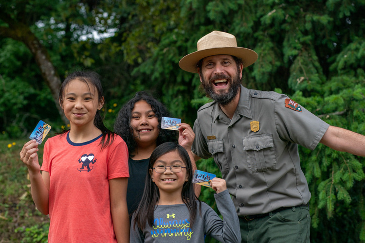 park ranger with students holding passes with a forest backdrop